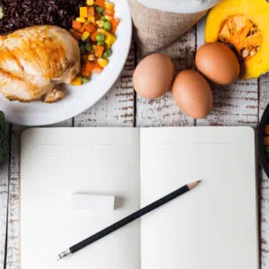 Open journal with pencil and eraser surrounded by healthy food