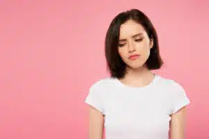 sad looking woman against pink background