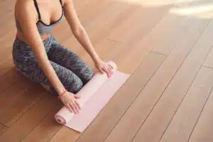 woman rolling up yoga mat after exercising to help with period pain