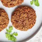 Sweet potato, quinoa and black bean burger on white plate with parsley garnish