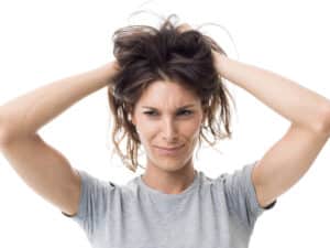 Women with bith hands in greasy hair in grey t shirt