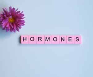 blue background with pink scrabble tiles spelling "hormones"