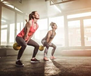 two women doing kettle bell workput in empty gym